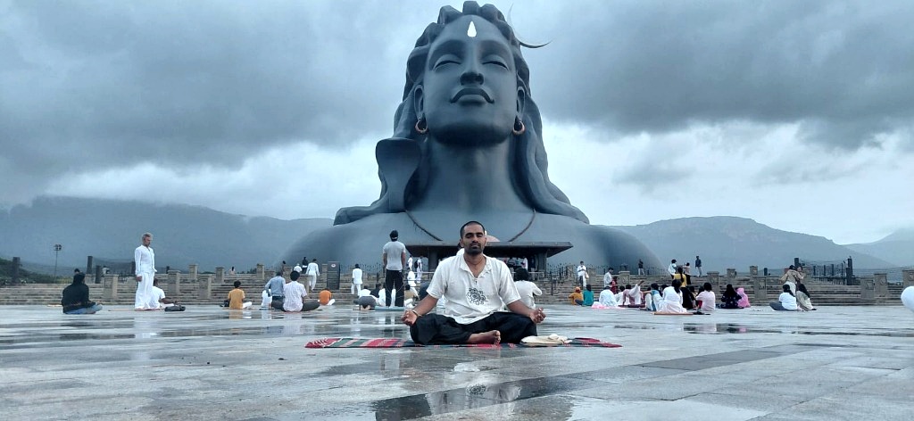 Akhilesh Gowda meditating in front of the massive black stone Adiyogi Shiva statue at the Isha Foundation in Coimbatore